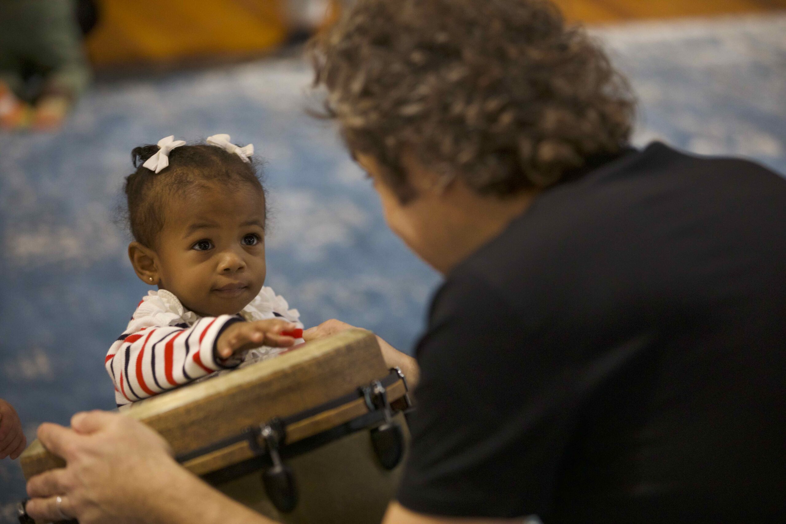 Preschooler playing a djembe drum in music class.