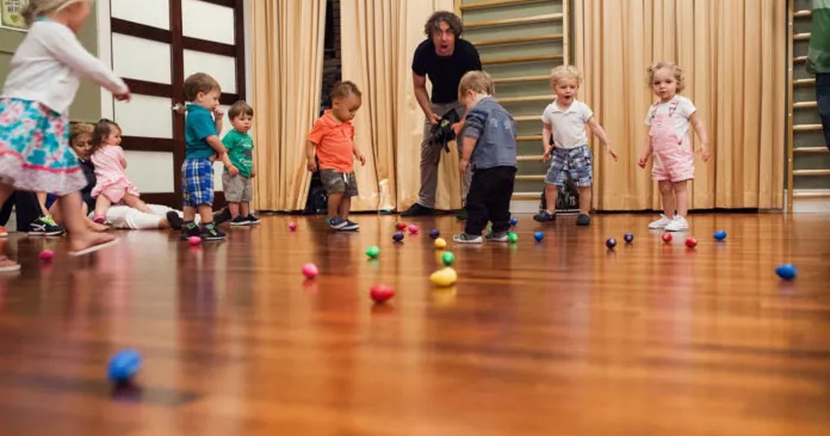 Toddlers moving among colorful shaker balls on a studio floor