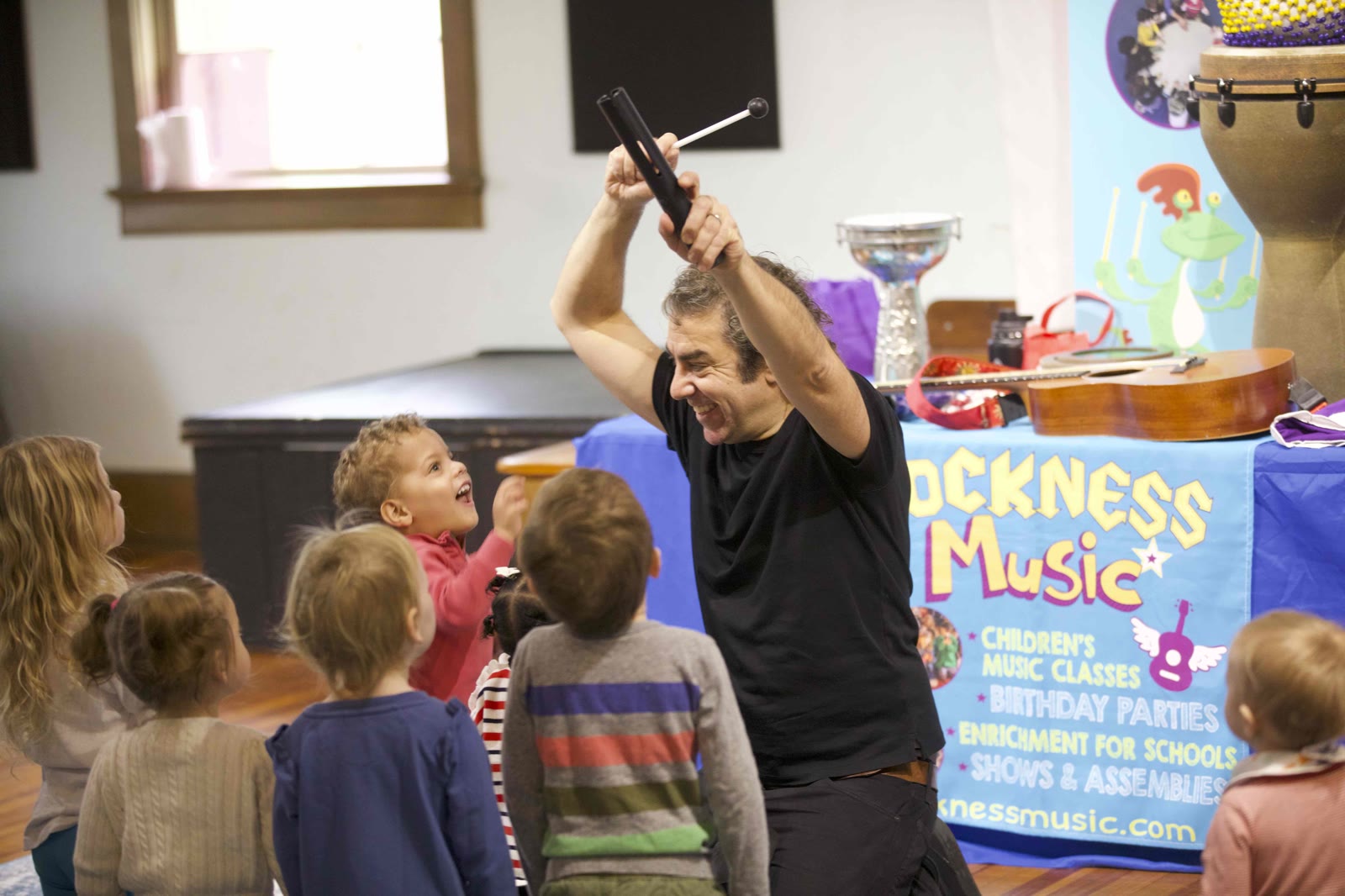 Mr. Michael introducing a new instrument to toddlers at a Rockness Music class