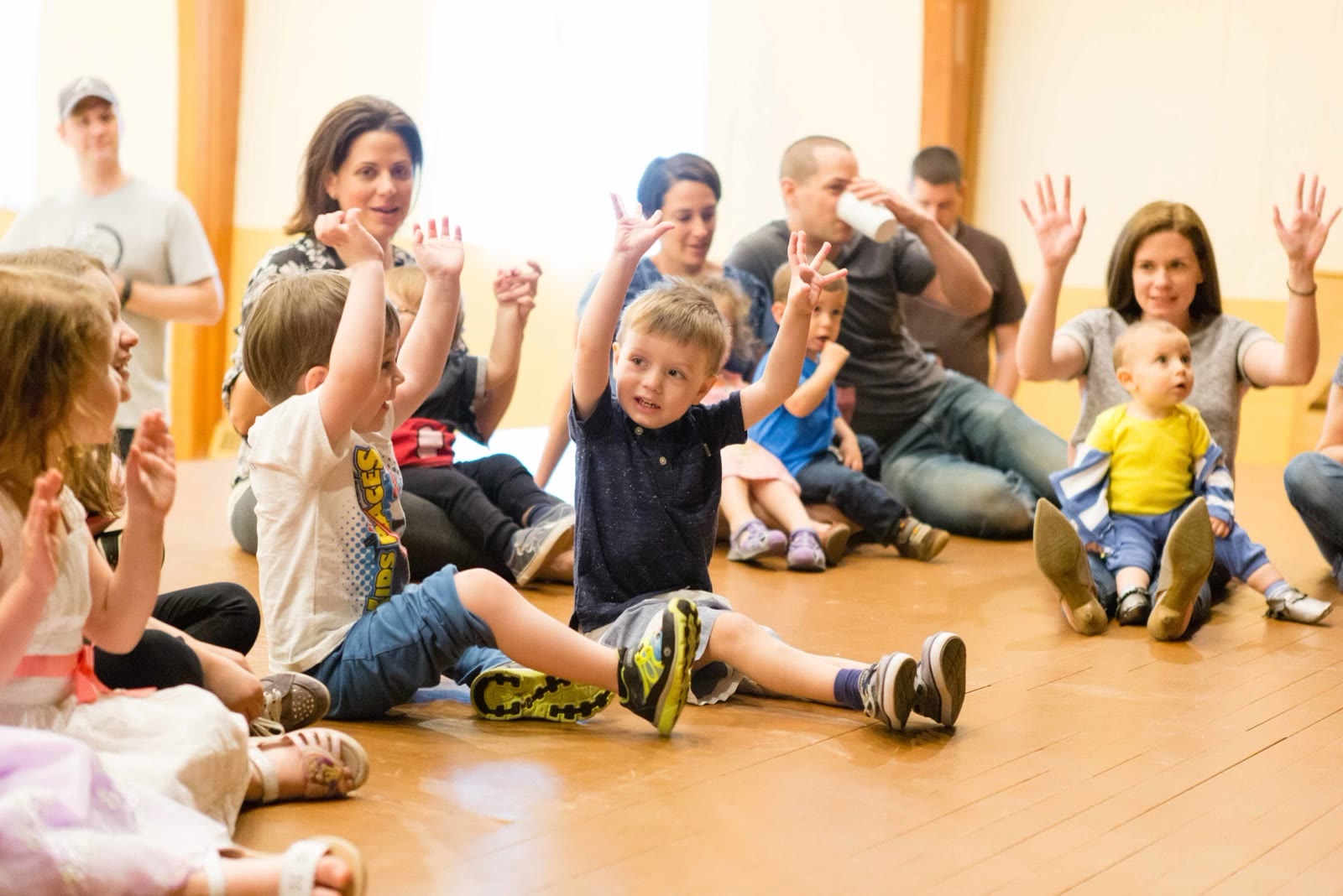 Kids and grown-ups in a circle with hands up during a Rockness Music party