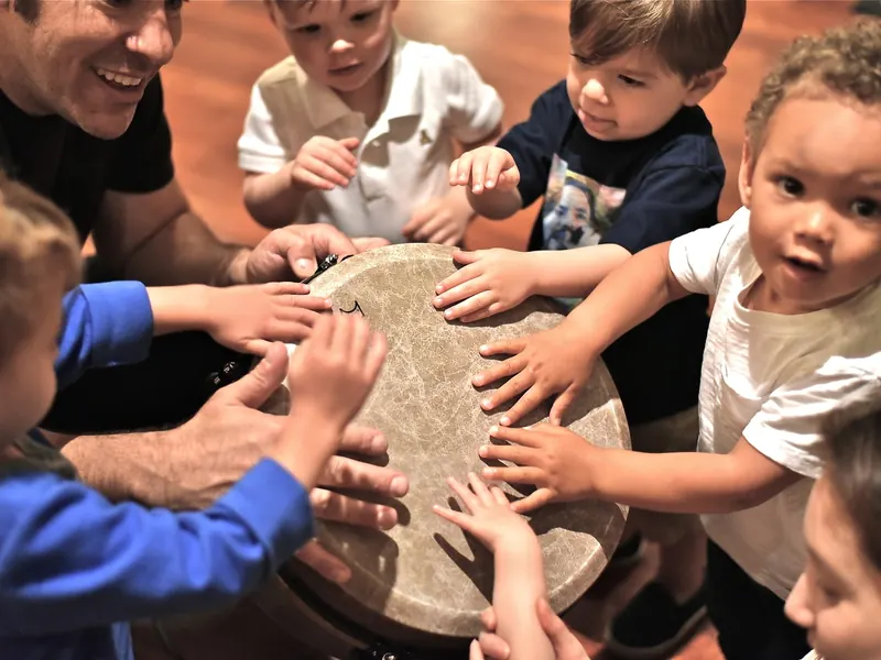 Preschoolers playing a drum together at a school program