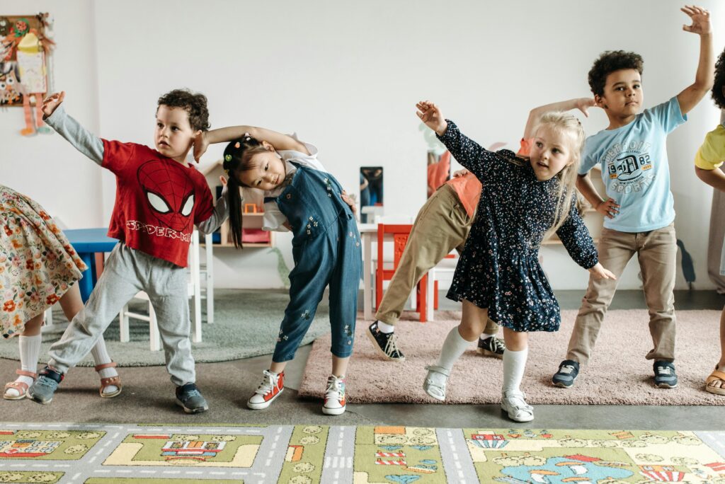 Teacher leading preschoolers in simple yoga stretches indoors