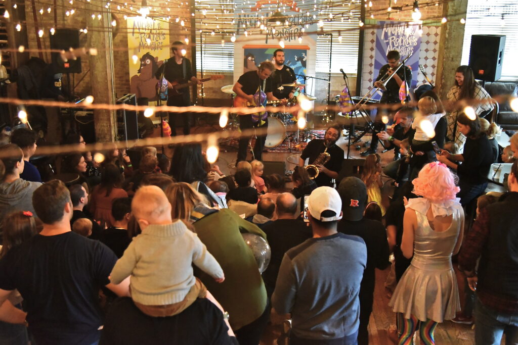 Michael and the Rockness Monsters performing a free live kids show as families and children dance together.